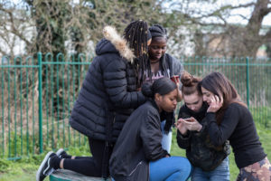 Young people in North London checking their phones.