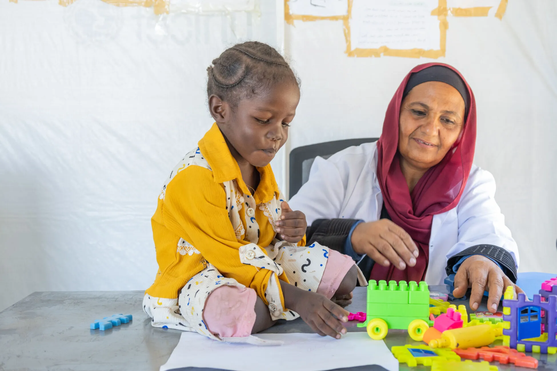 A four-year-old plays with their toys next to a mental health specialist.